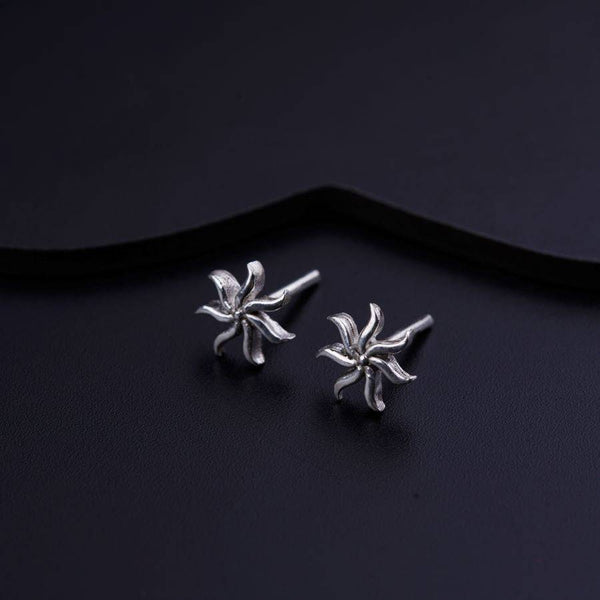 a pair of silver flower earrings on a black background