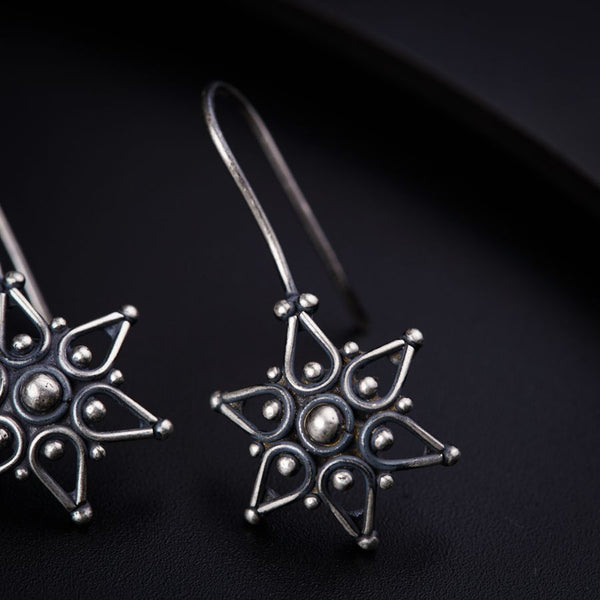 a pair of silver earrings on a black surface