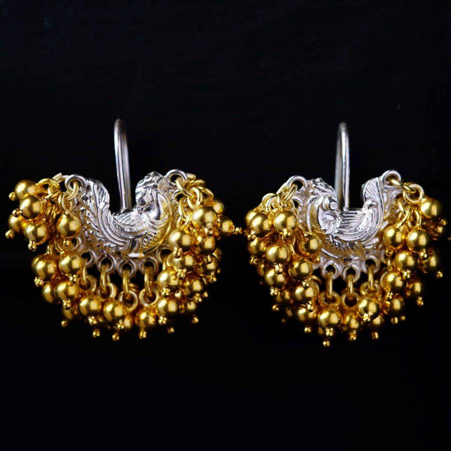 a pair of gold and silver earrings on a black background