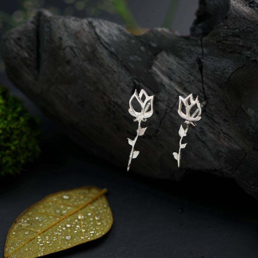 a pair of flower earrings sitting on top of a leaf