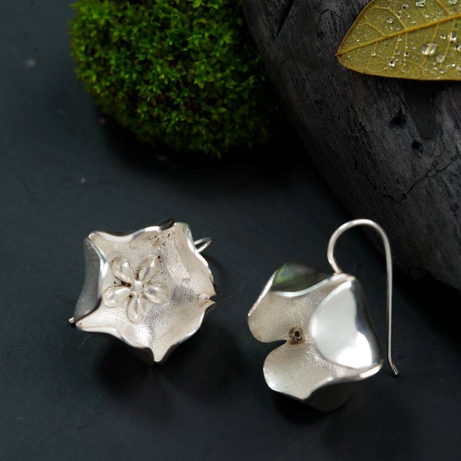 a pair of silver earrings sitting on top of a table