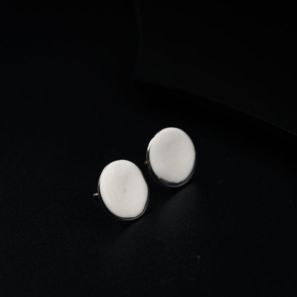 a pair of white earrings sitting on top of a black surface