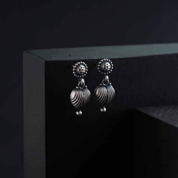 a pair of silver earrings on a black surface