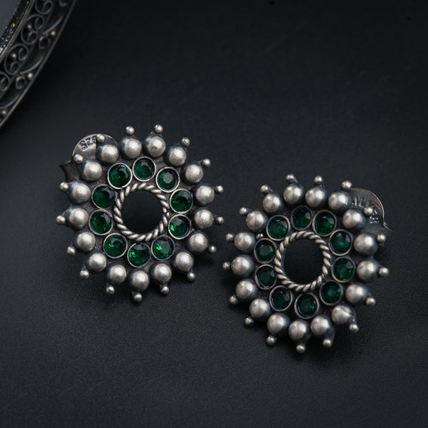 a pair of green and silver earrings on a black surface