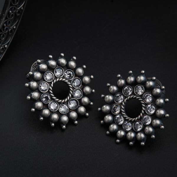 a pair of silver earrings on a black surface
