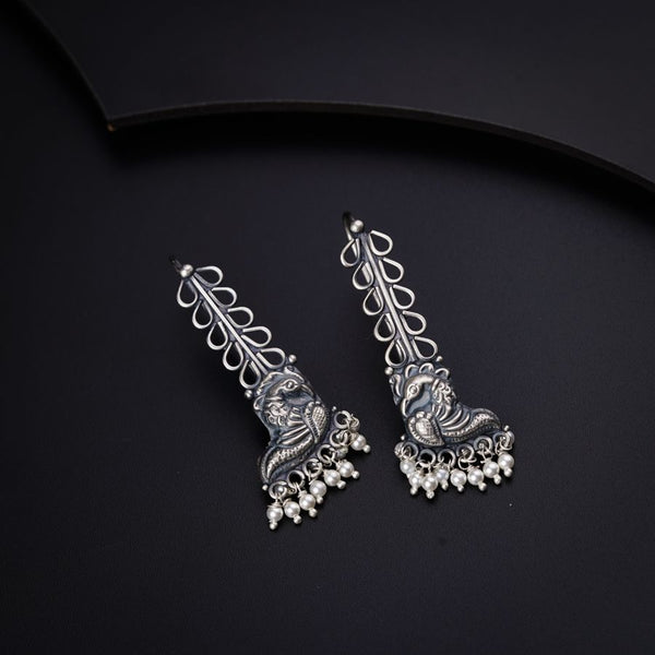 a pair of silver toned earrings on a black background