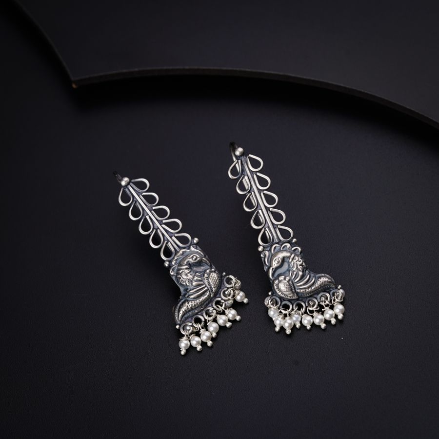 a pair of silver toned earrings on a black background