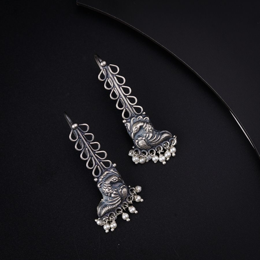a pair of silver colored earrings on a black background