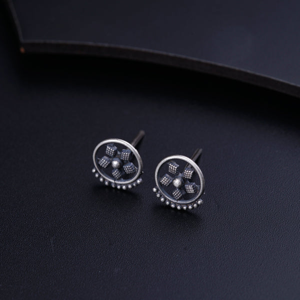 a pair of silver earrings on a black surface