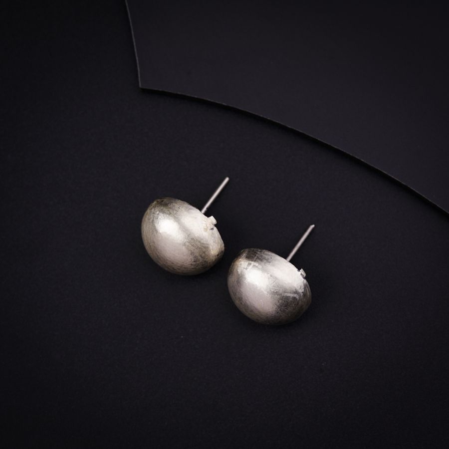 a pair of silver earrings sitting on top of a black surface