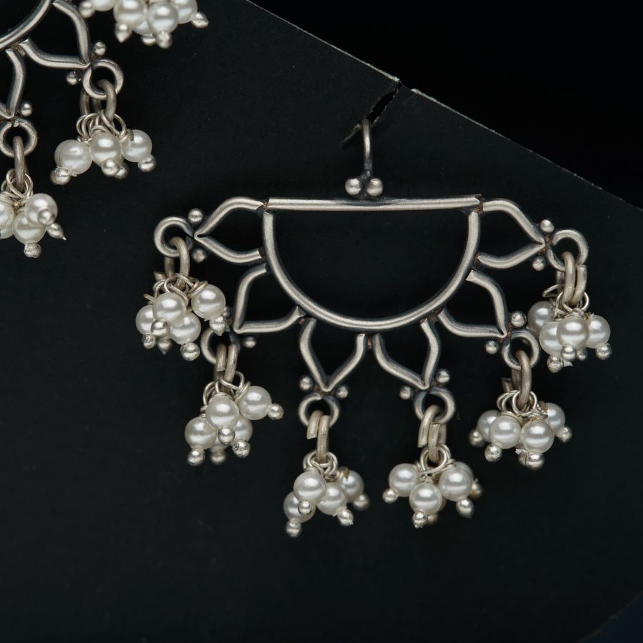 a pair of earrings with pearls hanging from it