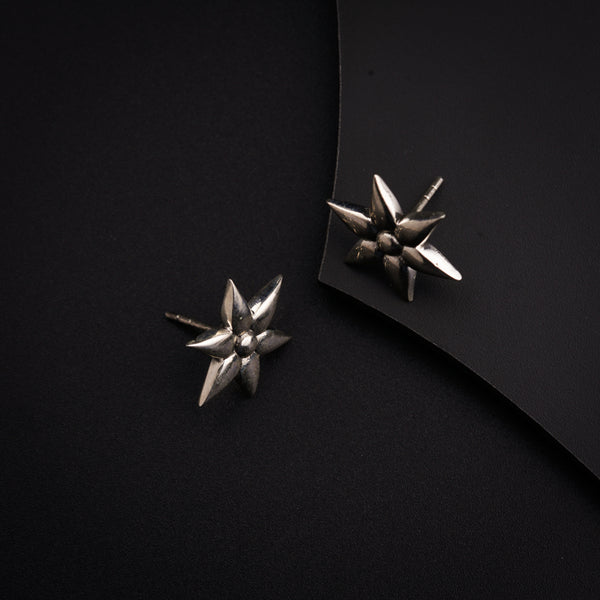 a pair of silver earrings sitting on top of a black surface