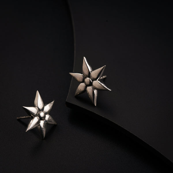 a pair of silver earrings sitting on top of a black surface