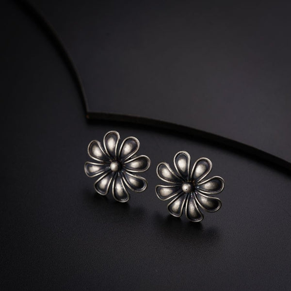 a pair of silver flower earrings on a black surface