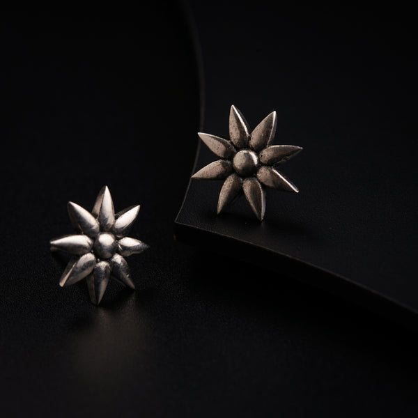 a pair of silver earrings sitting on top of a black surface