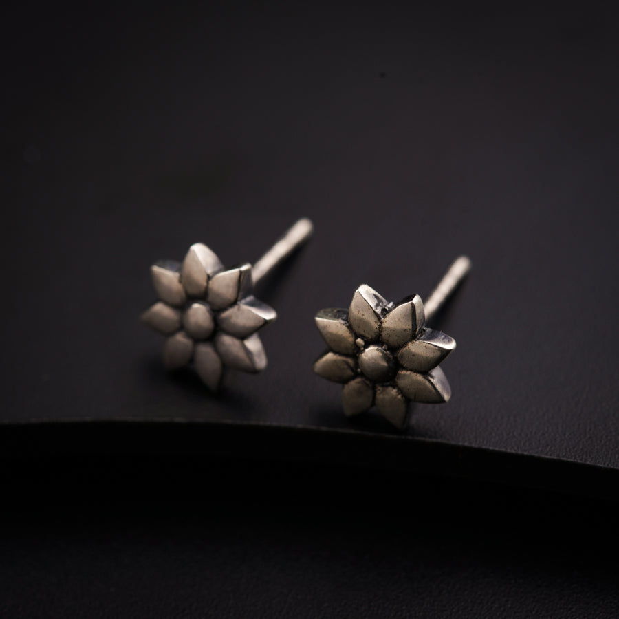 a pair of silver studs sitting on top of a black surface