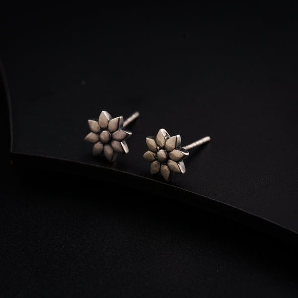 a pair of silver earrings on a black surface