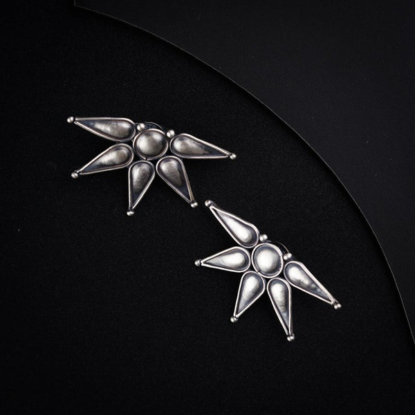 a pair of silver earrings on a black background