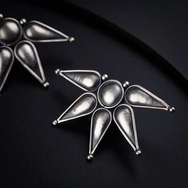 a pair of silver earrings sitting on top of a table