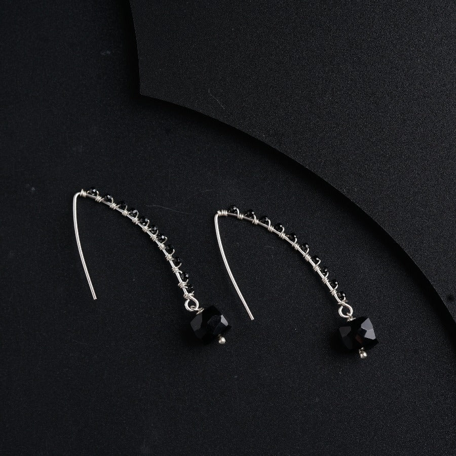a pair of black and silver earrings on a black surface