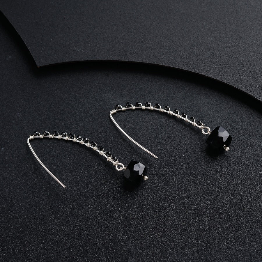 a pair of black and silver earrings on a black surface