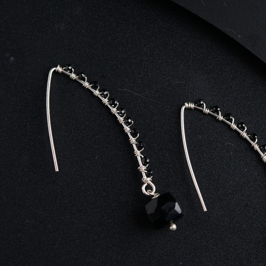 a pair of black and silver earrings on a black surface