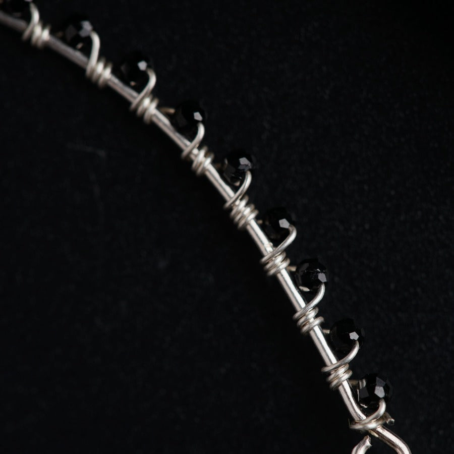 a silver chain with black beads on a black background