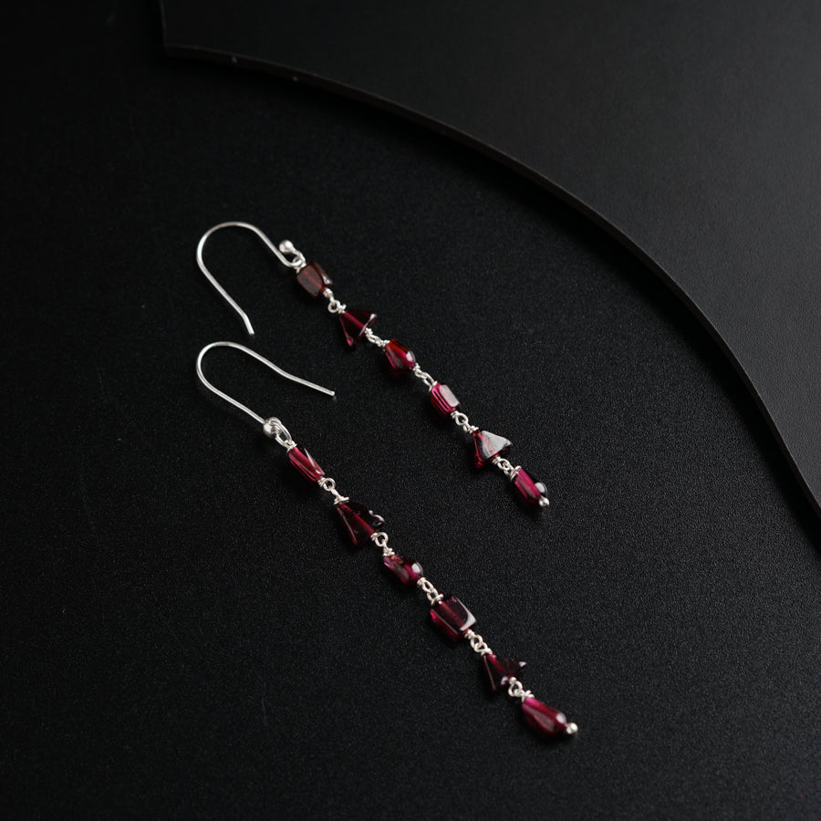 a pair of red and silver earrings on a black surface