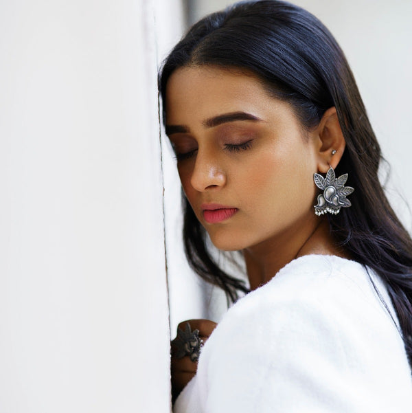 a woman wearing a white robe and a pair of earrings