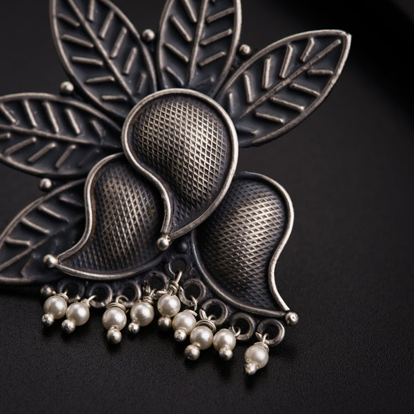 a close up of a brooch with pearls