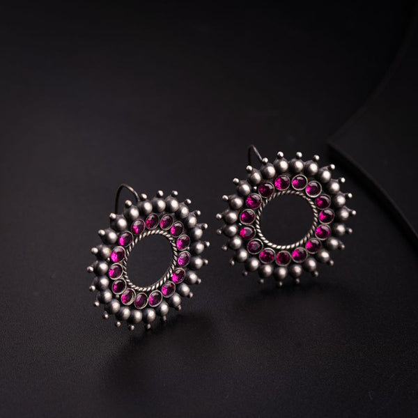 a pair of pink and silver earrings on a black surface