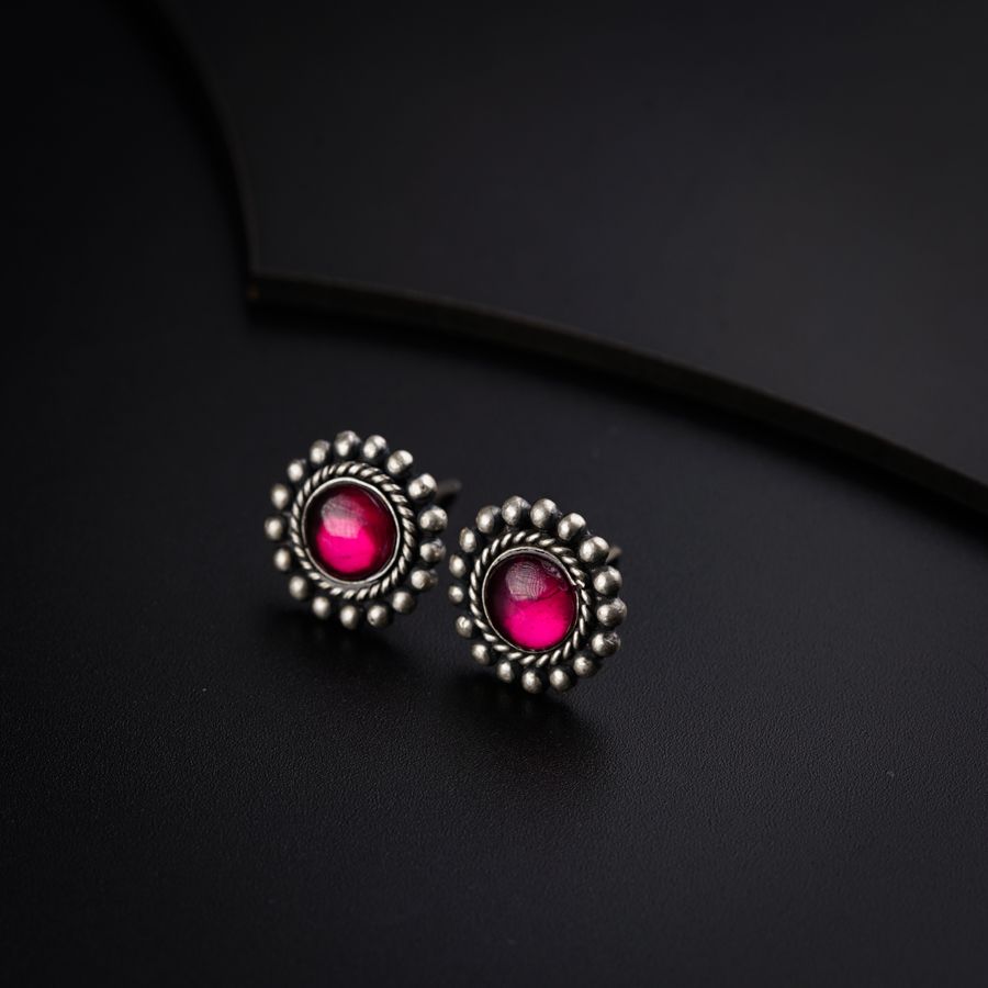 a pair of pink earrings on a black surface