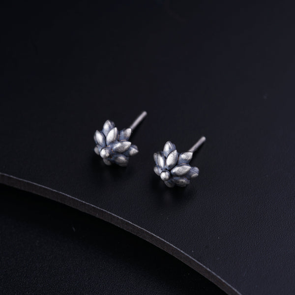 a pair of silver earrings sitting on top of a black surface