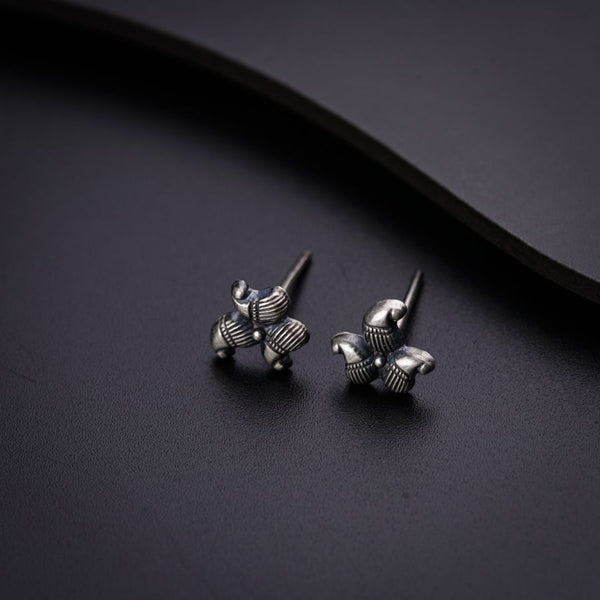 a pair of silver earrings on a black surface