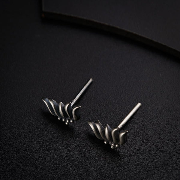 a pair of silver earrings sitting on top of a black surface
