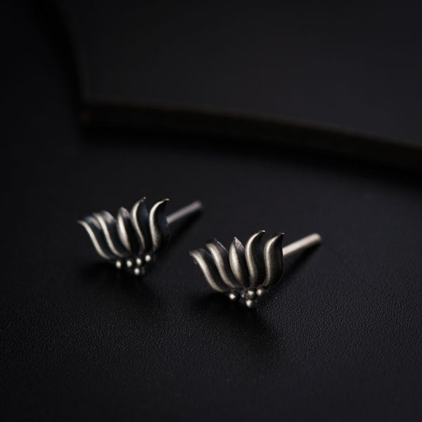 a pair of silver earrings sitting on top of a black surface