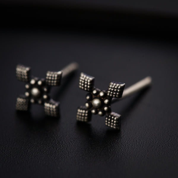 a pair of silver earrings on a black surface