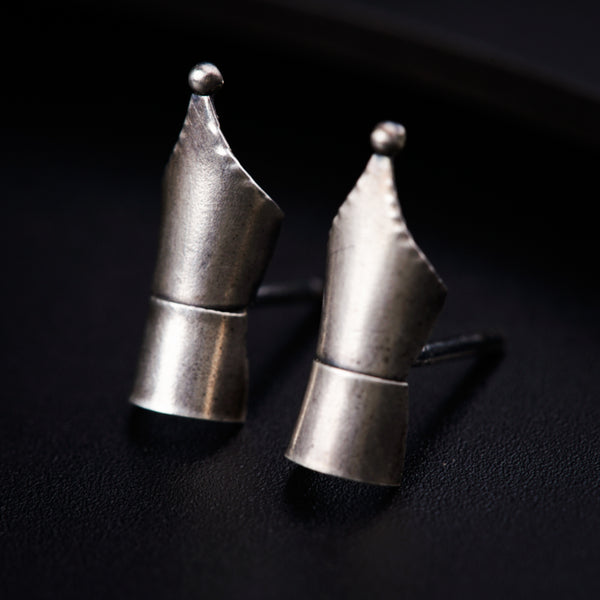 a pair of silver earrings sitting on top of a table