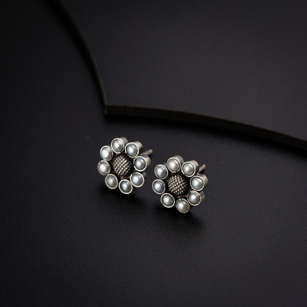 a pair of silver and pearl earrings on a black surface