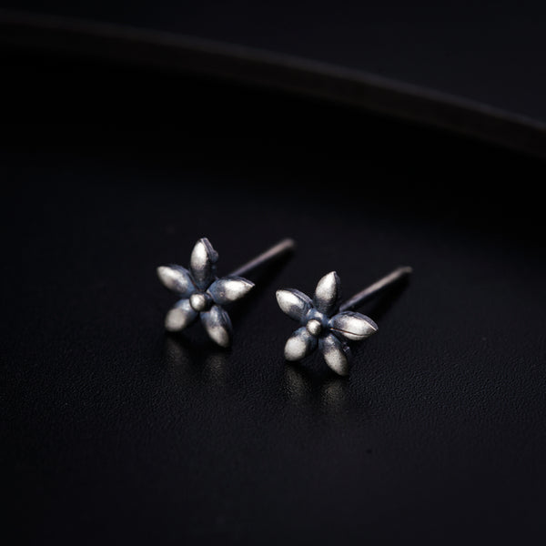 a pair of silver earrings on a black surface