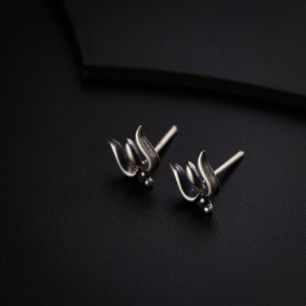 a pair of silver earrings sitting on top of a black surface