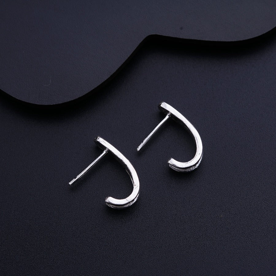 a pair of silver earrings sitting on top of a black surface