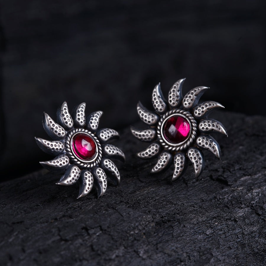 a pair of red stone earrings on a rock