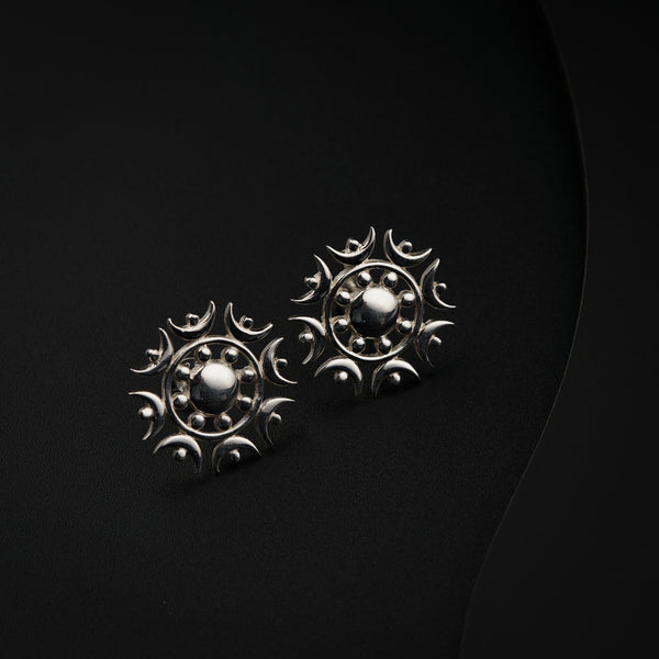a pair of silver earrings sitting on top of a black surface