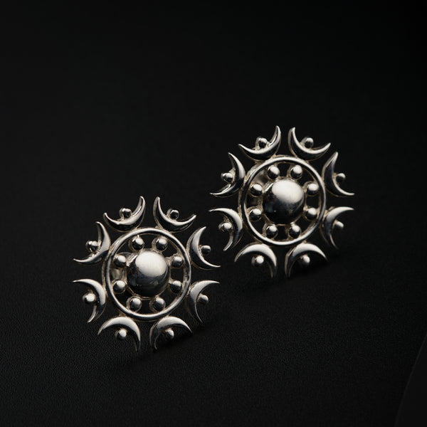 a pair of silver earrings on a black background