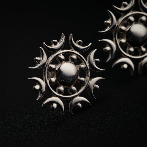 a pair of silver earrings on a black background