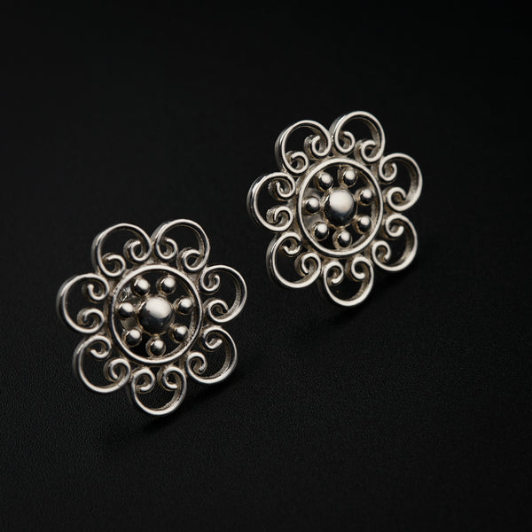 a pair of silver earrings on a black background