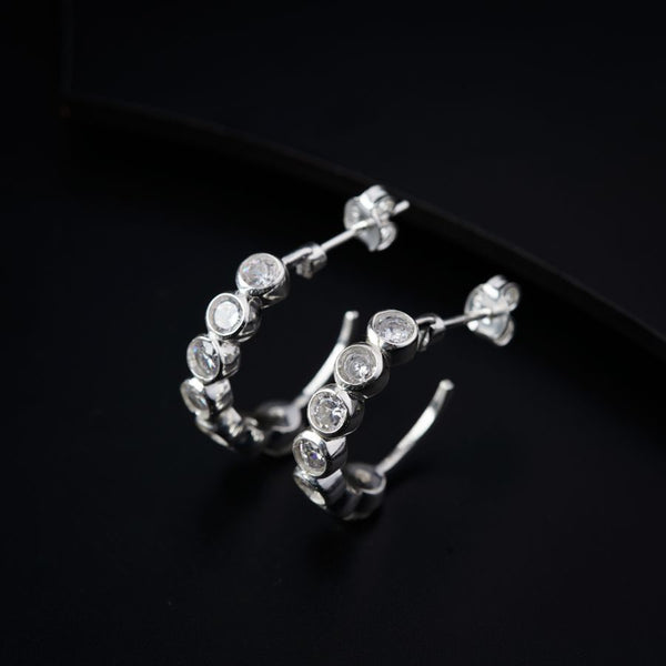 a pair of silver hoop earrings on a black surface