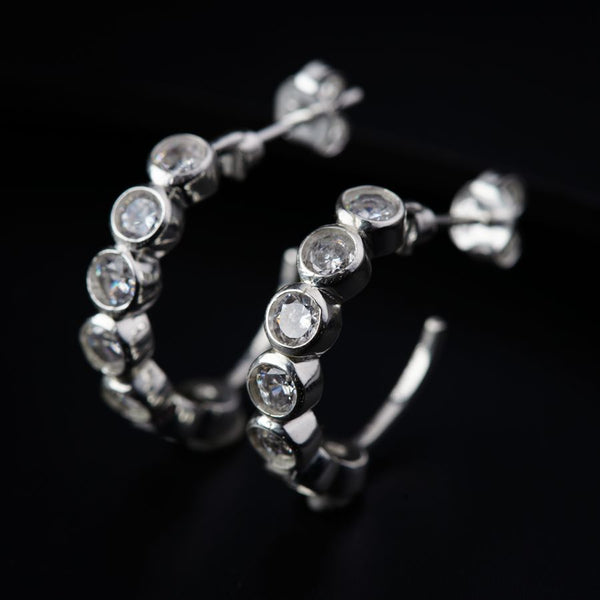 a pair of diamond hoop earrings on a black background