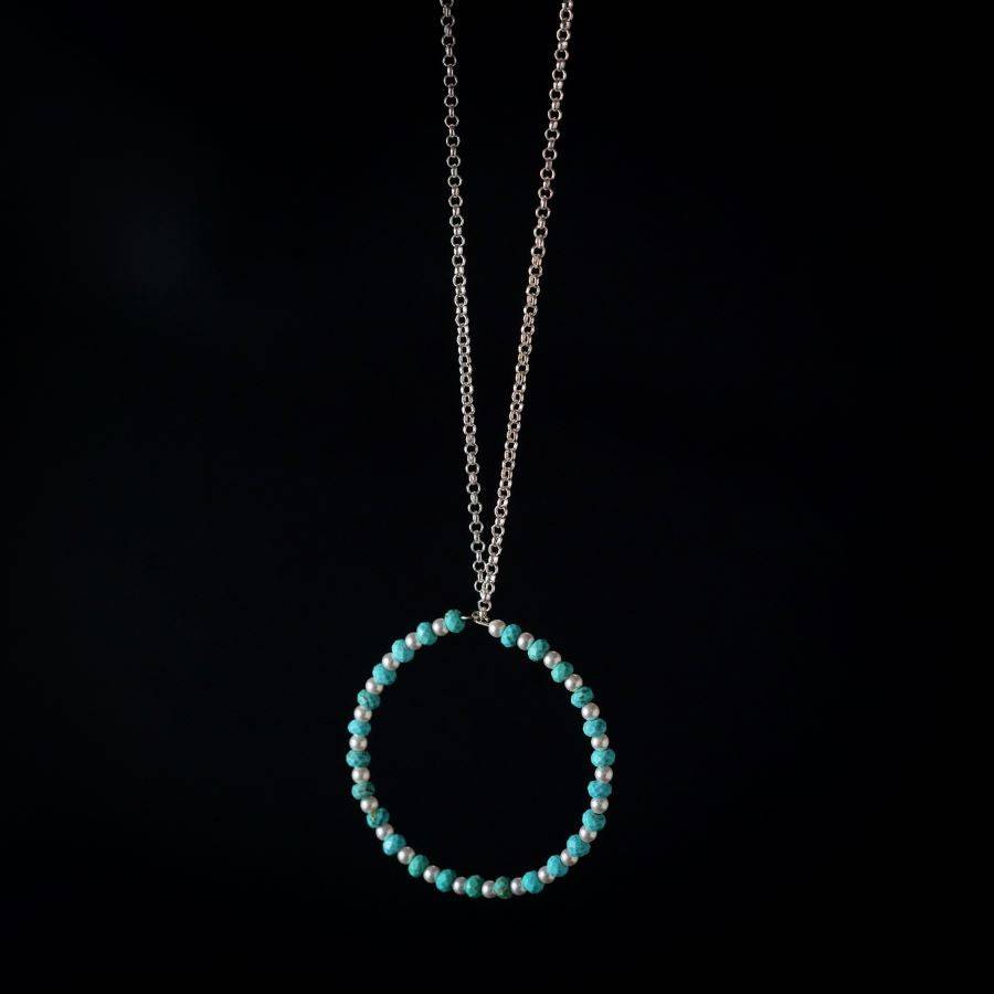 a blue beaded necklace with a circle on a chain